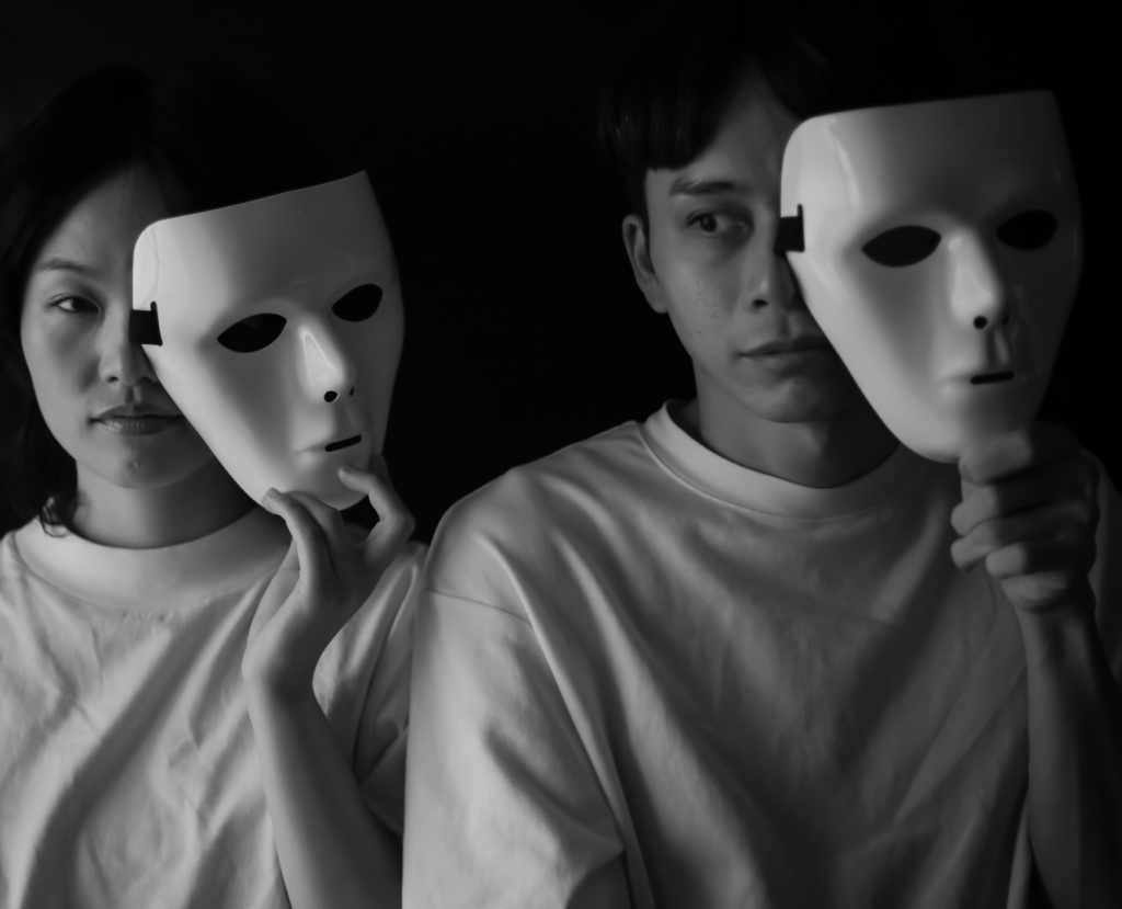 A man and women holding masks covering half they face.